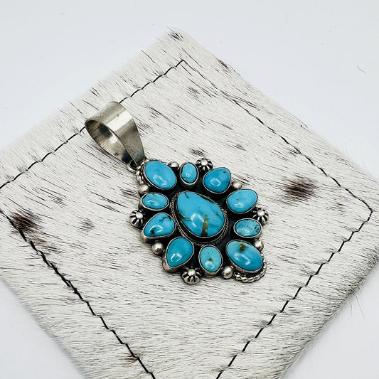 Angled view of the turquoise cluster pendant showing bezels, stamped silver flowers and dot accents