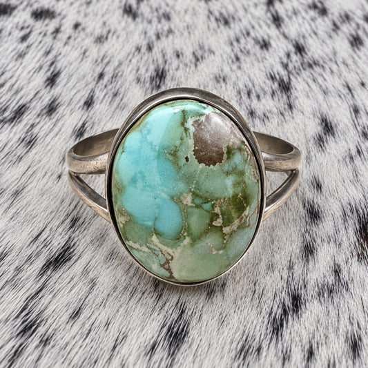 Sonoran Turquoise Ring by Susan Cooke — closeup view on gray-and-white cowhide