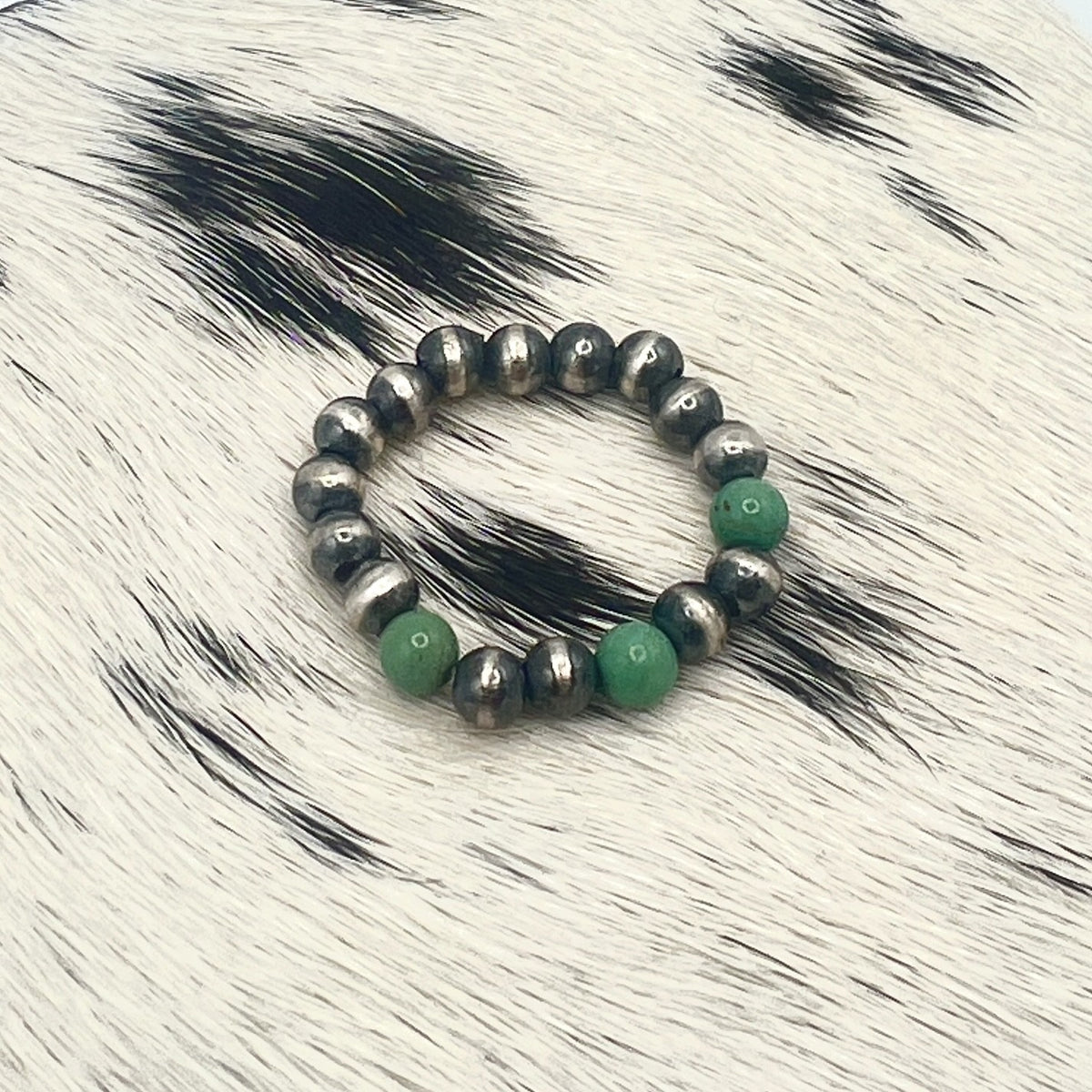 Green turquoise Desert Pearl stretch ring with 4mm sterling silver beads on a cowhide mat
