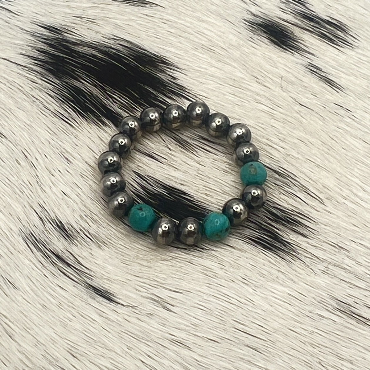 Blue turquoise Desert Pearl stretch ring with 4mm sterling silver beads on a cowhide mat