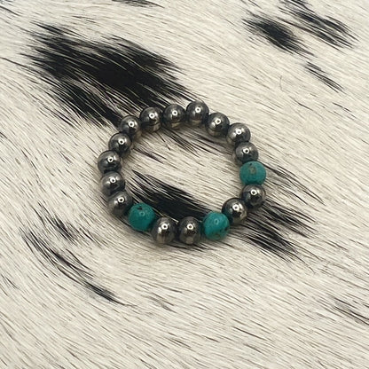 Blue turquoise Desert Pearl stretch ring with 4mm sterling silver beads on a cowhide mat