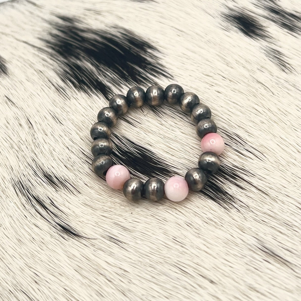 Pink conch Desert Pearl stretch ring with 4mm sterling silver beads on a cowhide mat