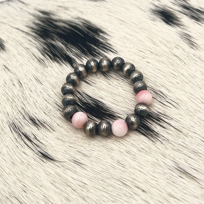 Pink conch Desert Pearl stretch ring with 4mm sterling silver beads on a cowhide mat