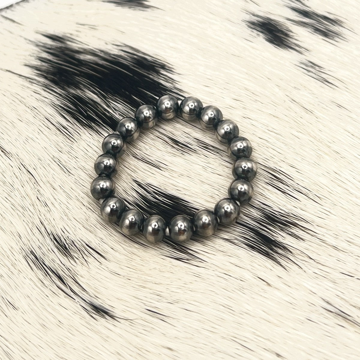 All silver Desert Pearl stretch ring with 4mm sterling silver beads on a cowhide mat