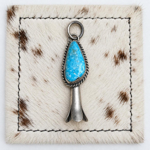 Susan Cooke bright blue turquoise blossom pendant, front view on cowhide