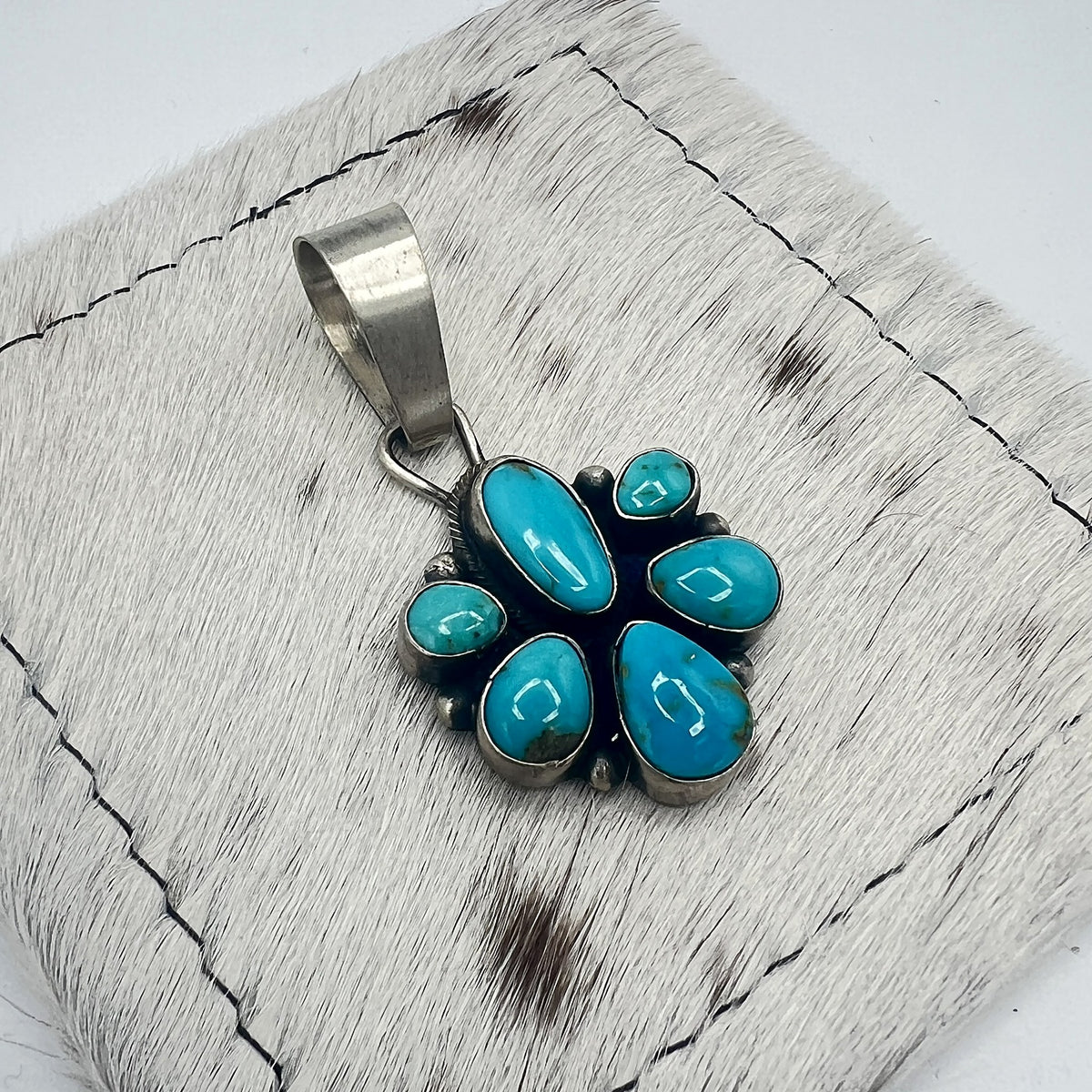 Angled view of the Sonoran turquoise cluster pendant showing hand-formed bezels and silver dot accents