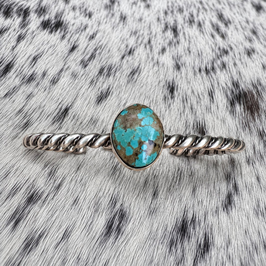 Elaine Tahe Navajo Artist Turquoise and Silver Twisted Wire Bracelet on gray-and-white cowhide
