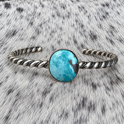 Elaine Tahe Navajo Artist Turquoise Bracelets in Sterling Silver on gray-and-white cowhide