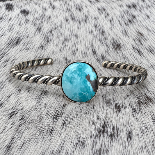 Elaine Tahe Navajo Artist Turquoise Bracelets in Sterling Silver on gray-and-white cowhide