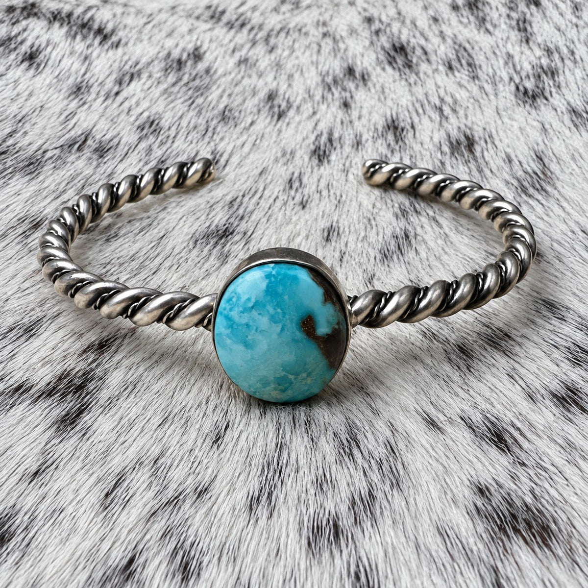 Elaine Tahe Navajo Artist Turquoise Bracelets in Sterling Silver — additional catalog view on gray-and-white cowhide