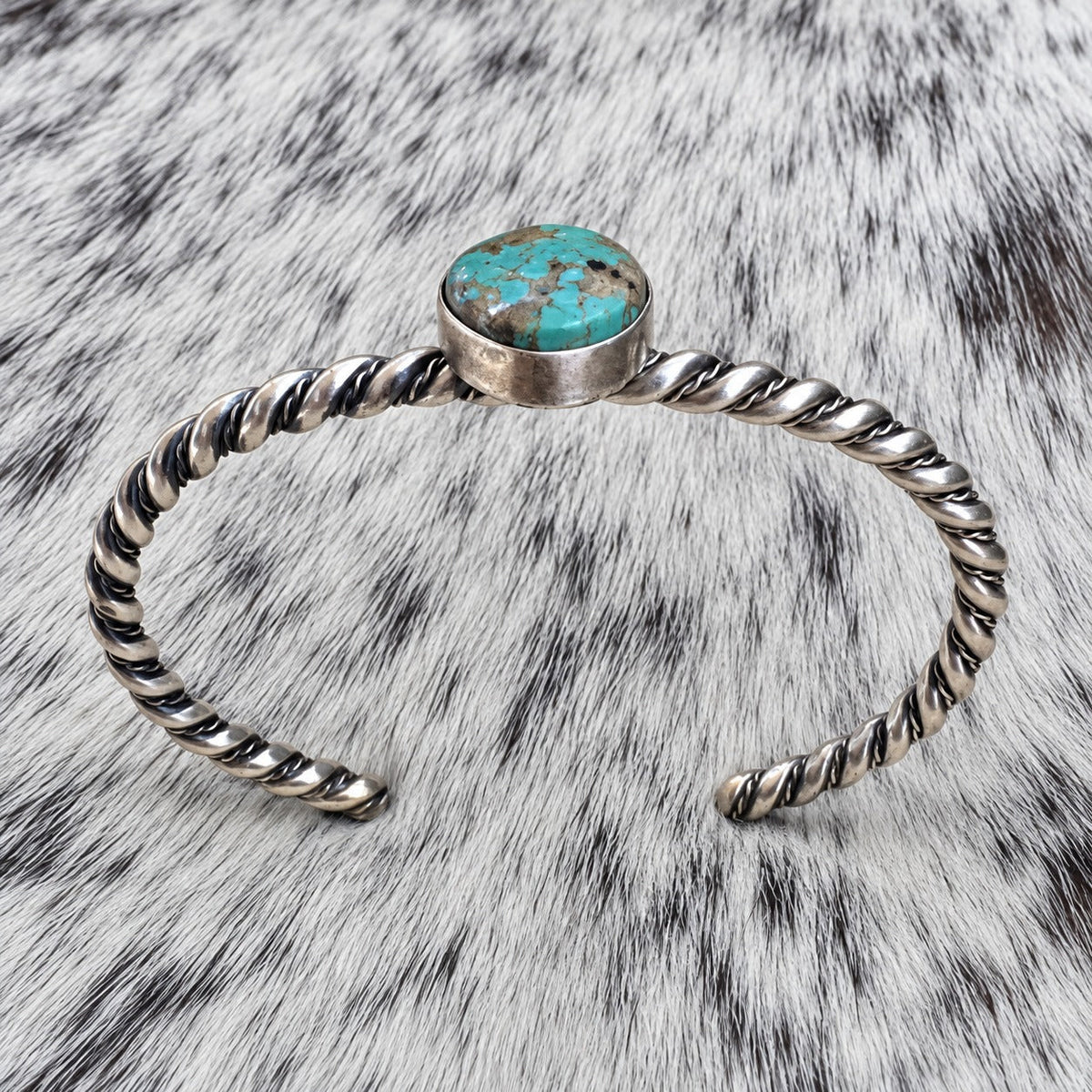 Elaine Tahe Navajo Artist Turquoise and Silver Twisted Wire Bracelet — additional catalog view on gray-and-white cowhide