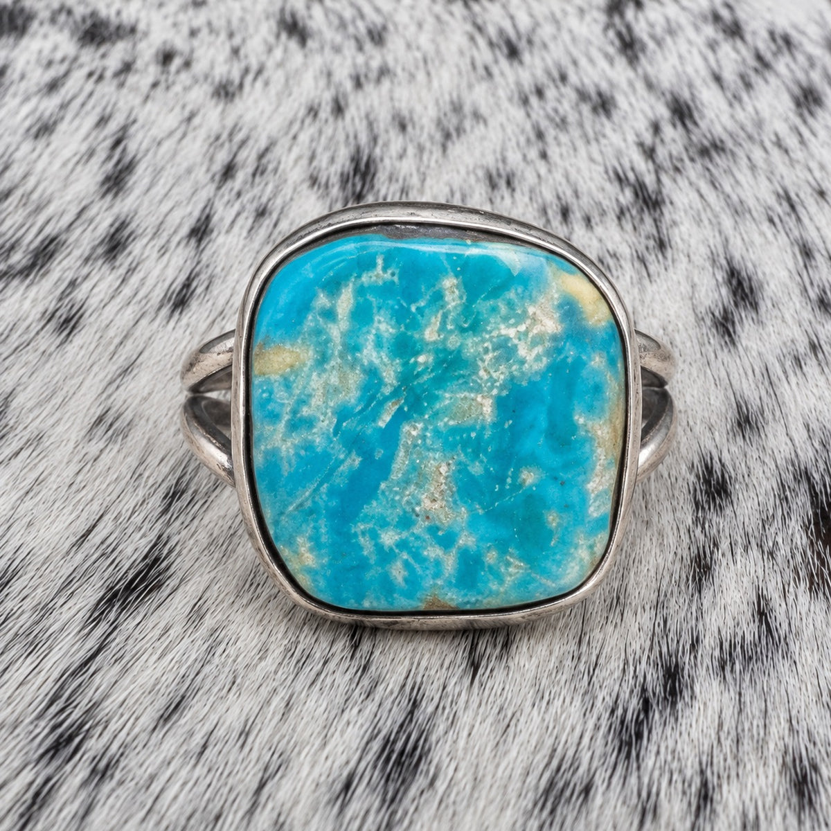 Freeform Turquoise Ring by Sheila Tso — closeup view on gray-and-white cowhide