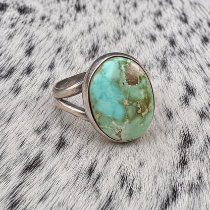 Sonoran Turquoise Ring by Susan Cooke — angle view on gray-and-white cowhide