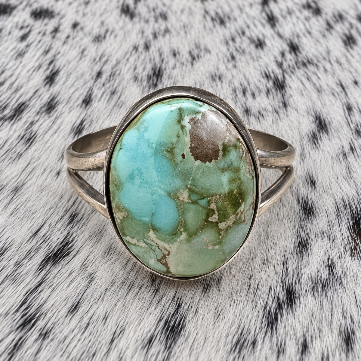 Sonoran Turquoise Ring by Susan Cooke — closeup view on gray-and-white cowhide