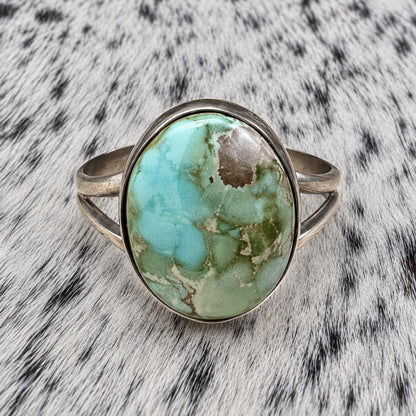 Sonoran Turquoise Ring by Susan Cooke — closeup view on gray-and-white cowhide