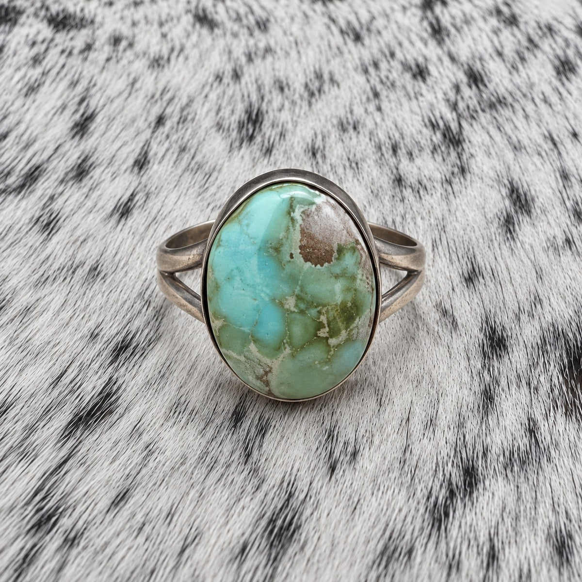 Sonoran Turquoise Ring by Susan Cooke — front view on gray-and-white cowhide